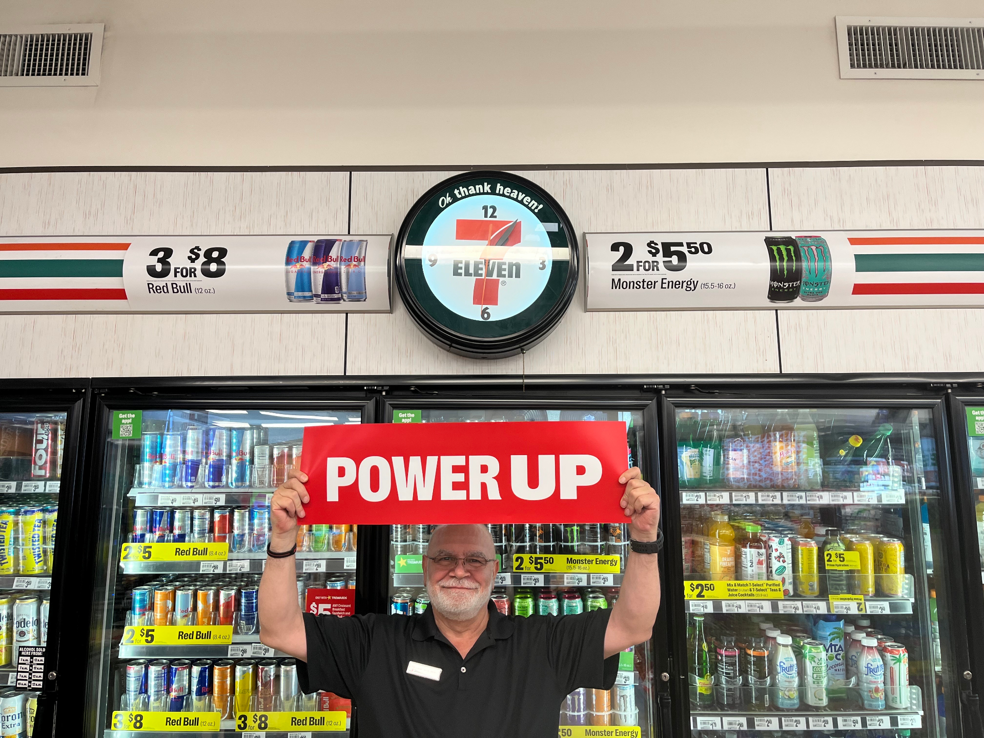 Sam holding a POWER UP sign at an energy drink cooler.